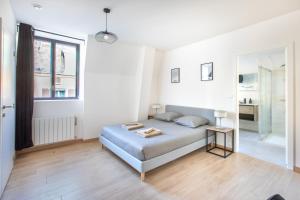 a white bedroom with a bed and a window at Romantic getaway with Jacuzzi, Downtown in Mulhouse