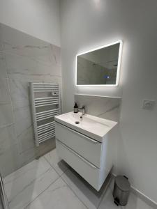 a white bathroom with a sink and a mirror at Maison de ville in Libourne