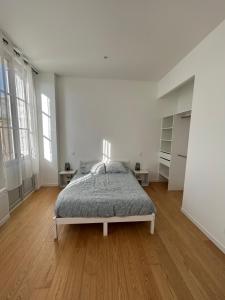 a white bedroom with a bed and a wooden floor at Maison de ville in Libourne