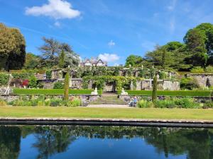 a man sitting on a bench next to a pond in a garden at Glascoed Guest House in Llandudno