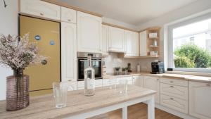 a kitchen with white cabinets and a vase of flowers on a counter at Captains Quarters 5 in Dahme in Dahme +21 photos