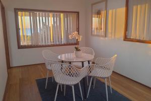 a table with chairs and a vase with flowers on it at Upper Esplanade Oceanview Escape in Bunbury +7 photos