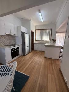 a large kitchen with white appliances and wooden floors at Upper Esplanade Oceanview Escape in Bunbury