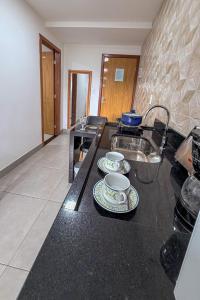 a kitchen with two cups and plates on a counter at Aeroporto e praia Studio Casal in Vitória