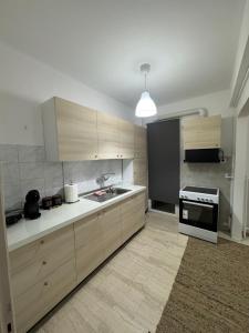 a kitchen with wooden cabinets and a sink and a stove at Dimitras Apartment with 3 bedrooms Elefsis in Eleusis