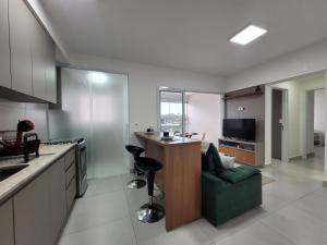 a kitchen with a green couch and a bar in it at Lavit 92 - Conforto, estilo e lazer com piscina e academia in Bauru