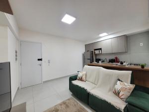 a living room with a green couch and a kitchen at Lavit 92 - Conforto, estilo e lazer com piscina e academia in Bauru