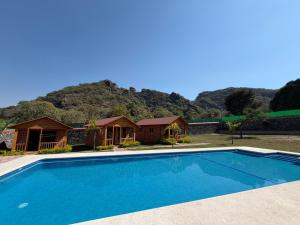 a swimming pool in front of a house with a mountain at Cabañas Tlaxomolco in Tepoztlán