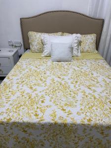 a bed with a yellow and white comforter and pillows at ajmicasita in Constanza