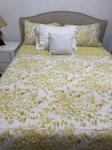a bed with a yellow and white bedspread with yellow flowers at ajmicasita in Constanza
