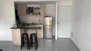 a kitchen with a refrigerator and a counter with stools at Balcones del Bosque 14 -402 in Restrepo