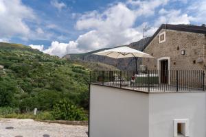 a building with a balcony with an umbrella at Le Vie del Borgo | 3 dimore indipendenti a Civita in Civita