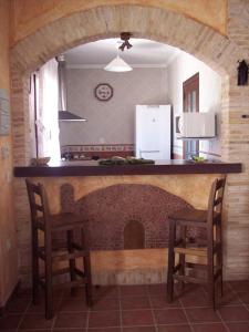 a kitchen with a counter with two chairs and a fireplace at Casa rural EL BOMBO in Tomelloso