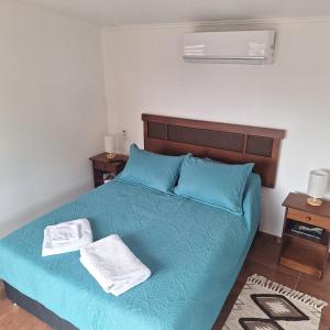 a bedroom with a blue bed with two towels on it at Cabaña Roquin Patagonia in Chile Chico
