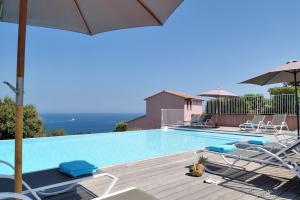a swimming pool with chairs and an umbrella at Résidence MARINA SERENA in Porto-Vecchio