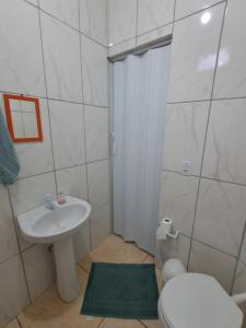 a white bathroom with a sink and a toilet at Suite Nomar in Brotas