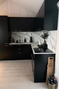 a kitchen with black cabinets and a sink at Lyngen Alps Inn in Lyngseidet