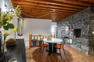 a room with a table and chairs and a stone wall at Casa Miradouro do Pesqueiro in Feteira Grande