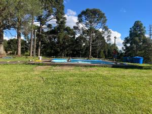 a swimming pool in a park with people in it at Galpão, Pousada Paraíso do Arruda in Lages