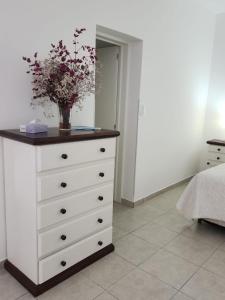 a dresser with a vase of flowers on top of it at Departamento 2 Viedma Centro in Viedma
