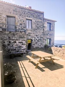a picnic table in front of a stone building at Casa Miradouro do Pesqueiro in Feteira Grande