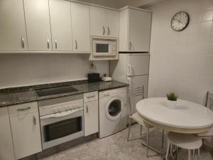 a kitchen with white cabinets and a table and a microwave at Casa Anita in Luarca