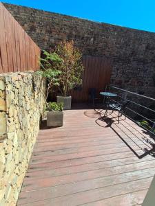 a wooden deck with a bench and a stone wall at Le Vrero Boutique Hotel in Colonia del Sacramento