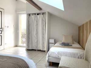 a white bedroom with a bed and a window at Puravida Apparts in Lagnieu