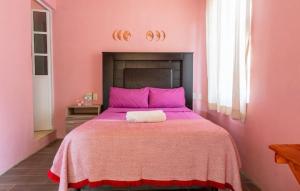 a pink bedroom with a large bed with pink sheets at POSADA CENTRO MAZUNTE RINCONCITo in Mazunte