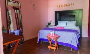 a bedroom with a large bed with a table at POSADA CENTRO MAZUNTE RINCONCITo in Mazunte +8 photos