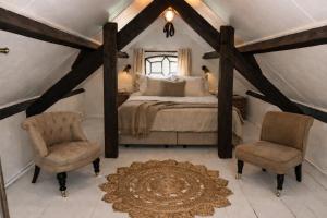 a bedroom with a large bed and two chairs at De Beijersche Stee , Landhuysje in Stolwijk