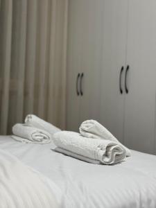 two towels sitting on a bed in front of a mirror at Golden Apartment 1 in Kamëz