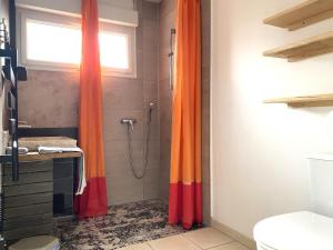a shower with an orange curtain in a bathroom at Puravida Apparts in Lagnieu +62 photos