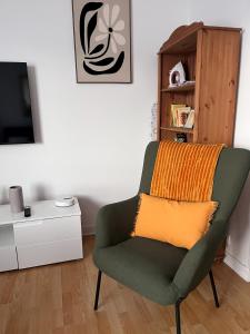 a living room with a green chair with an orange blanket at Ma première étoile in Joué-lès-Tours