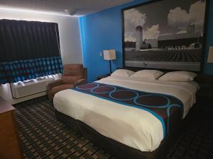 a hotel room with a large bed and a chair at Super 8 by Wyndham Lincoln West in Lincoln