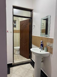 a bathroom with a sink and a toilet and a mirror at Luxx Homes #Unit B in Ruiru