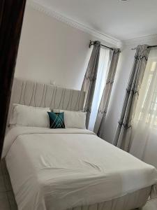 a bedroom with a white bed with curtains at Luxx Homes #Unit B in Ruiru
