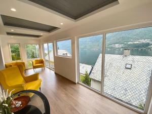 a living room with a yellow chair and large windows at Trolltunga Fjordview House, Odda in Odda