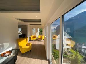 a living room with yellow chairs and a large window at Trolltunga Fjordview House, Odda in Odda
