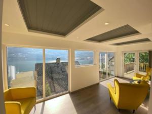 a living room with yellow chairs and large windows at Trolltunga Fjordview House, Odda in Odda +27 photos
