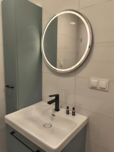 a white bathroom with a sink and a mirror at Aura Apartamenty 3 in Brzeg +19 photos