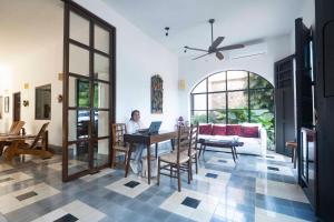 a woman sitting at a table with a laptop in a living room at Hotel Posada San Juan in Valladolid