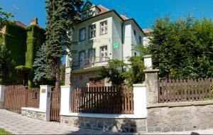 ein großes Haus mit einem Zaun davor in der Unterkunft Hotel Green House in Teplice