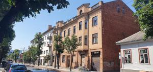 a large brick building on a street with cars parked in front at Kęstučio 66 apartamentai in Kaunas
