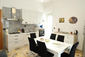 a white kitchen with a white table and chairs at Paradiso dell'Etna in Zafferana Etnea