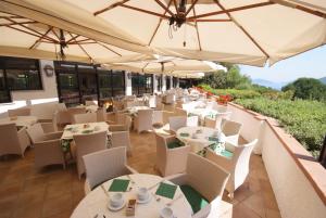 a patio area with tables, chairs and umbrellas at Hotel Valle Verde in Procchio