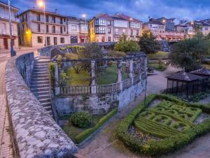 an old stone wall with a garden in a city at Casa MENDEZ - ALLARIZ in Ourense