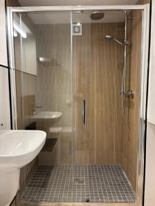 a shower with a glass door next to a sink at Stable Lodge in Killarney +24 photos