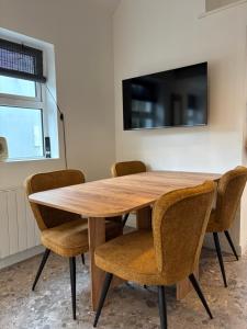 a wooden table with chairs and a tv on a wall at Stable Lodge in Killarney