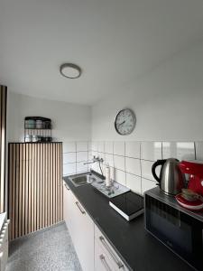 a kitchen with a sink and a clock on the wall at Domblick Apartment in Aachen